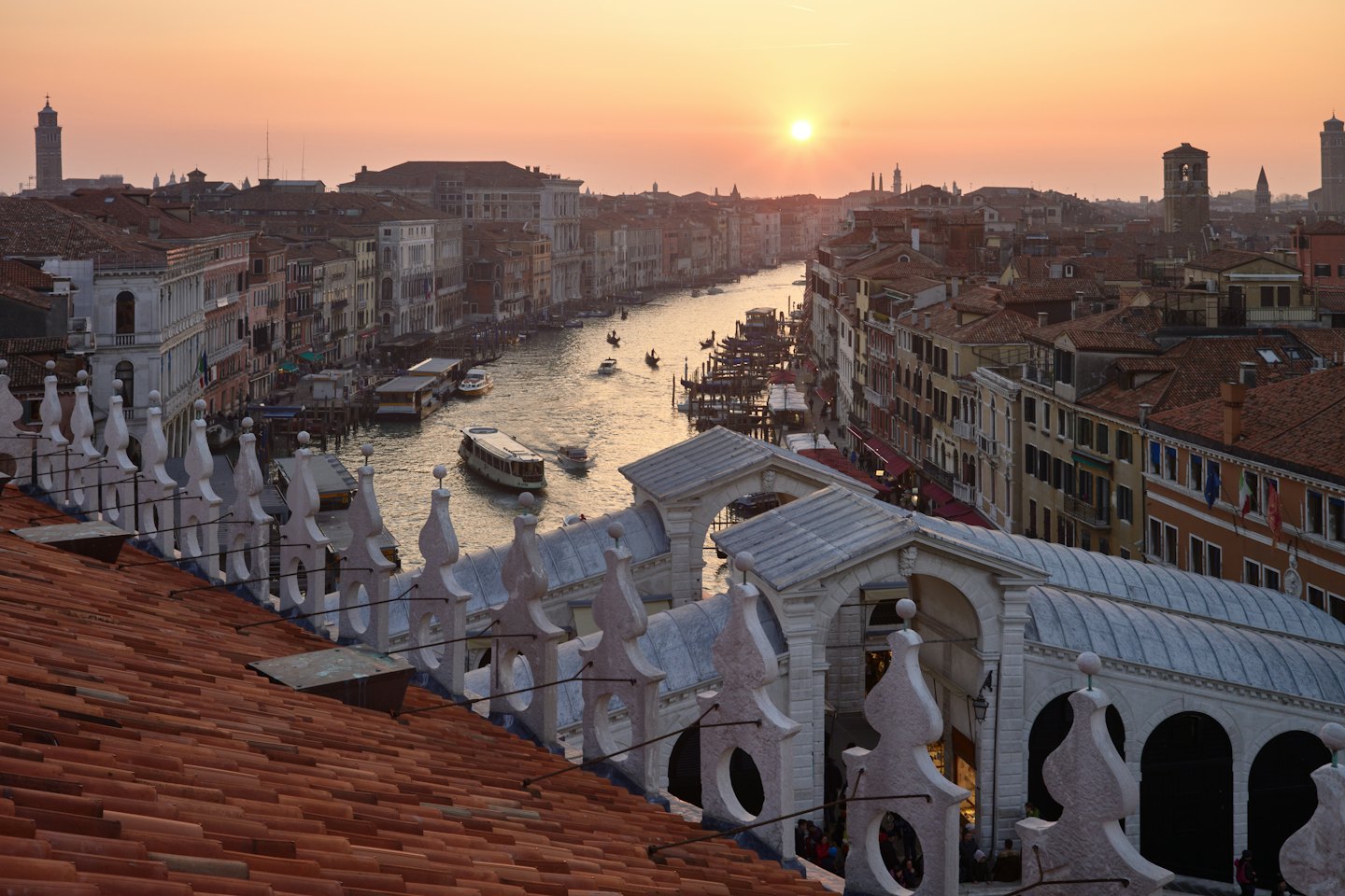 Boats navigate the Grand Canal near the historic Rialto Bridge.