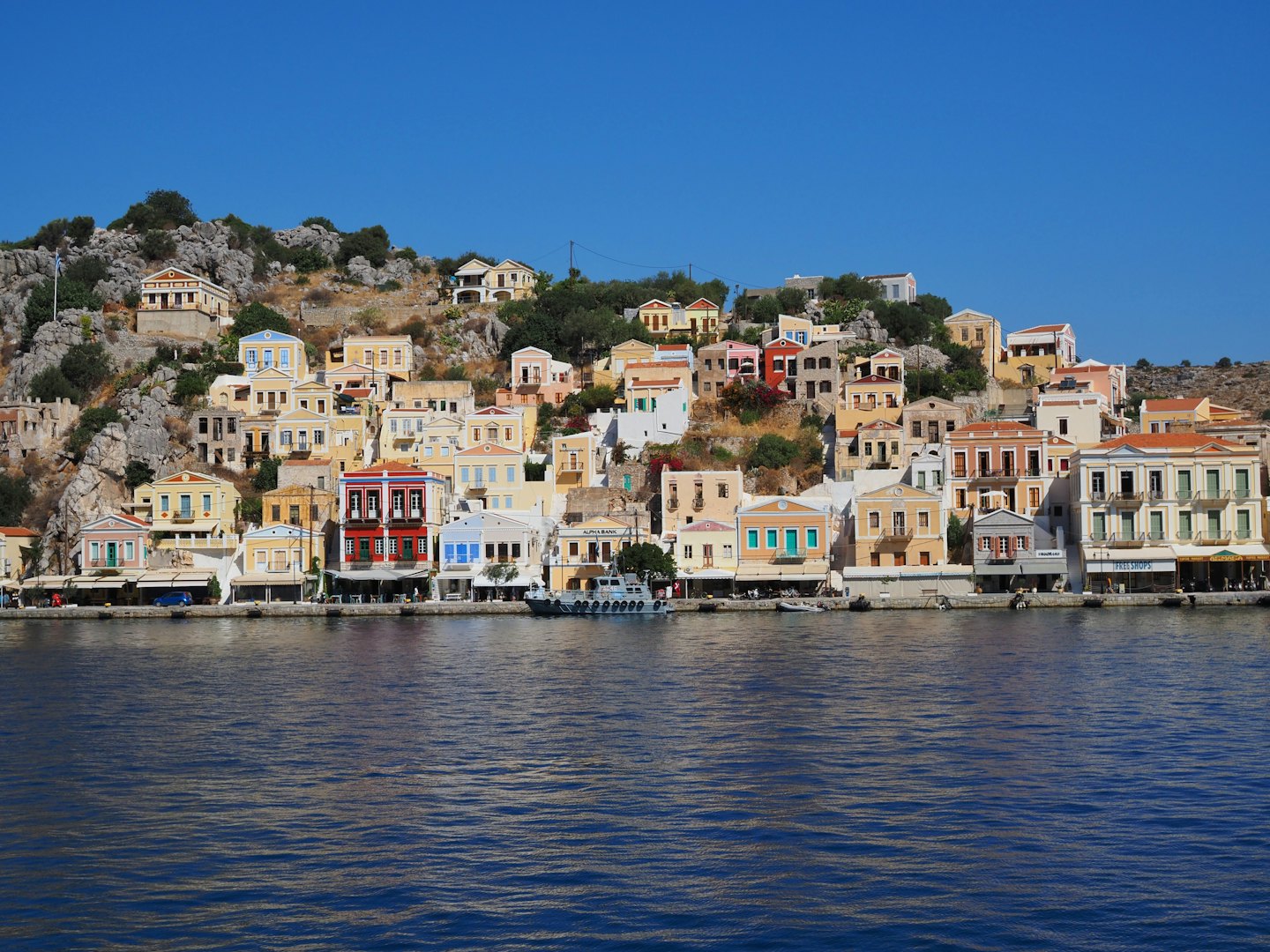 Colorful houses and shops built along a Mediterranean rocky coastline.