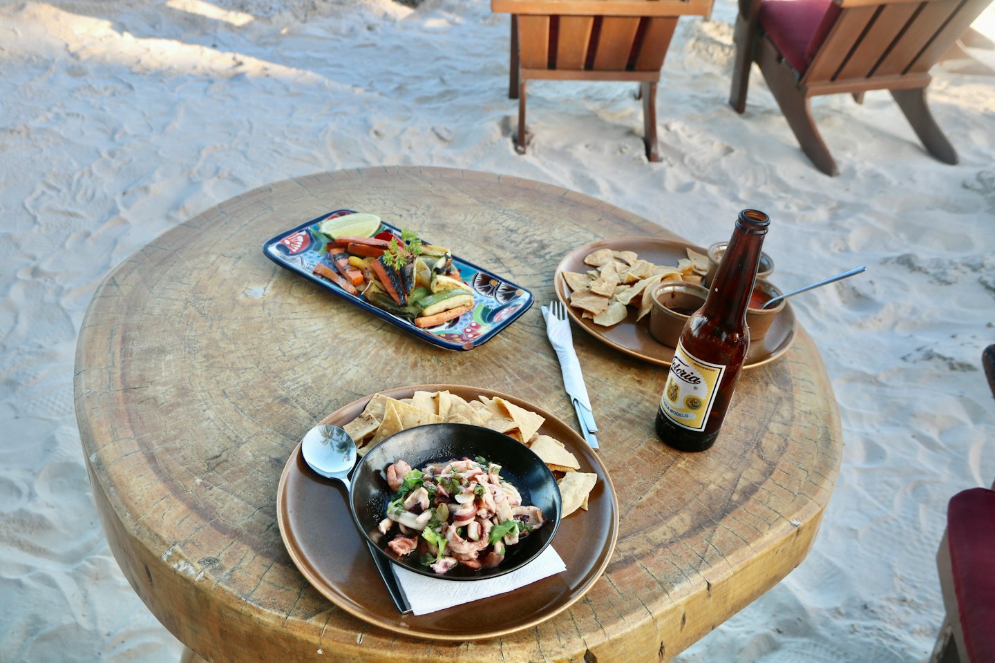 Grilled vegetables and snacks sit on a rustic wooden table.
