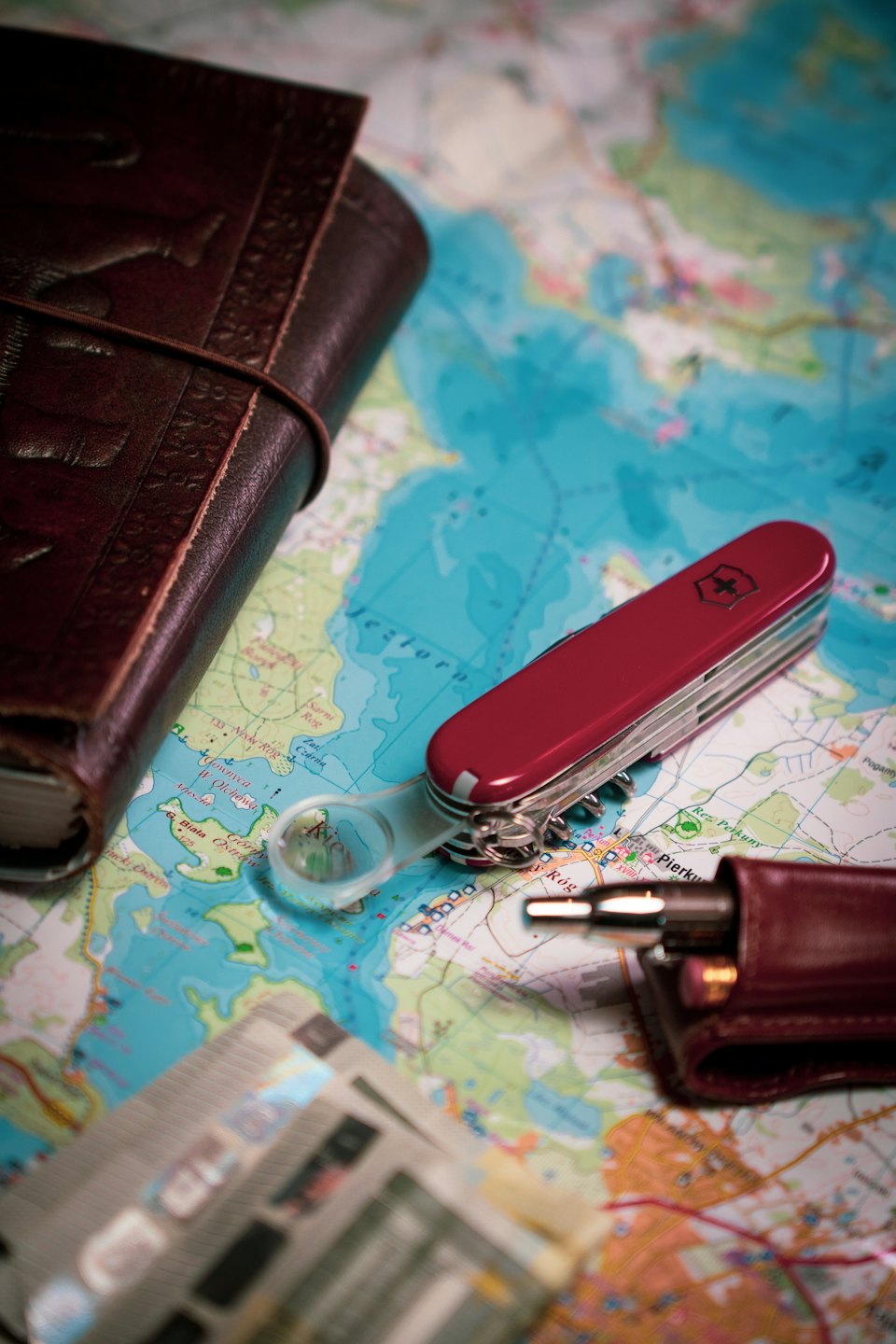 Travel essentials laid out on a map with a journal and multi-tool.
