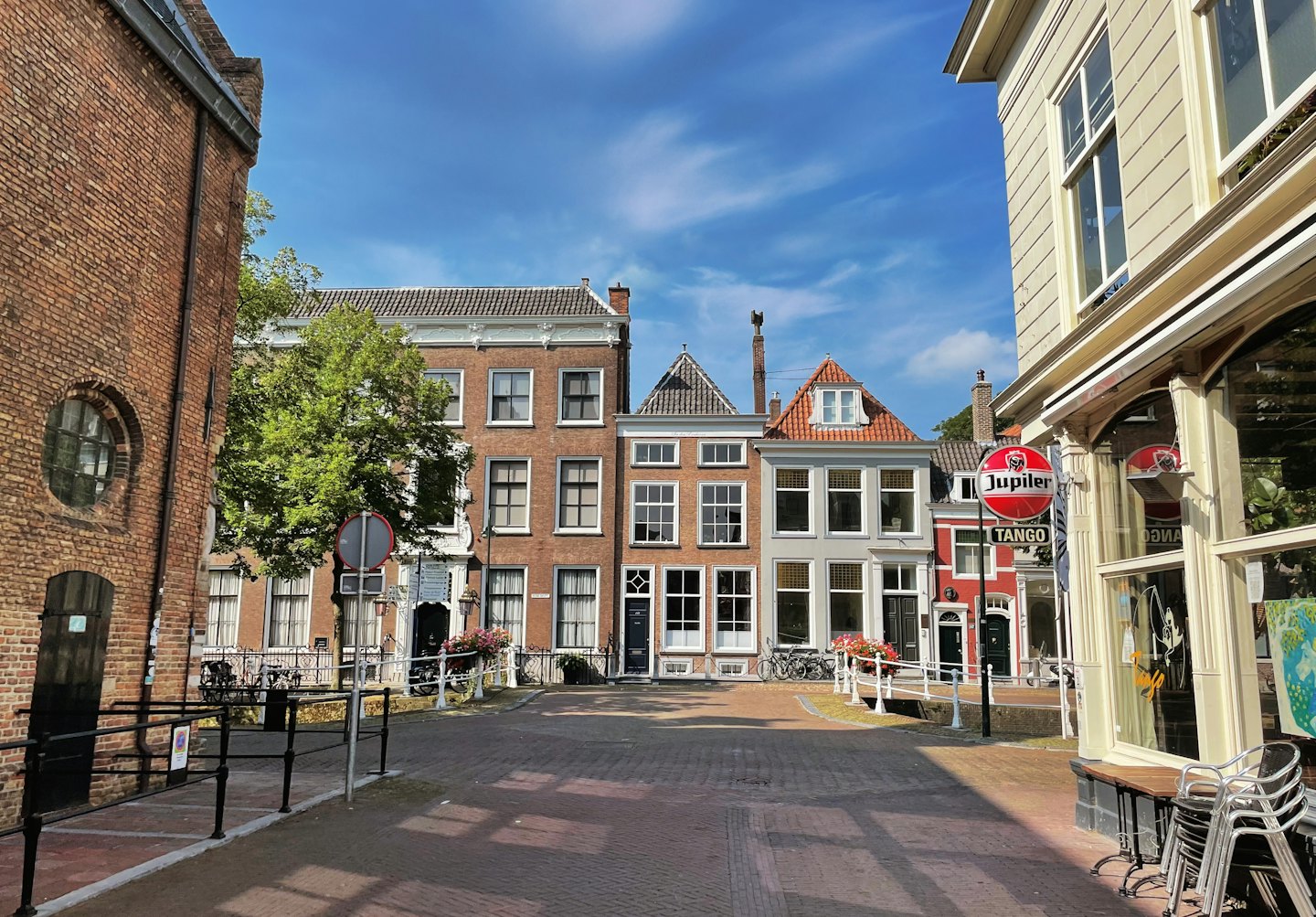 Cafe tables sit along a historic cobblestone European street.