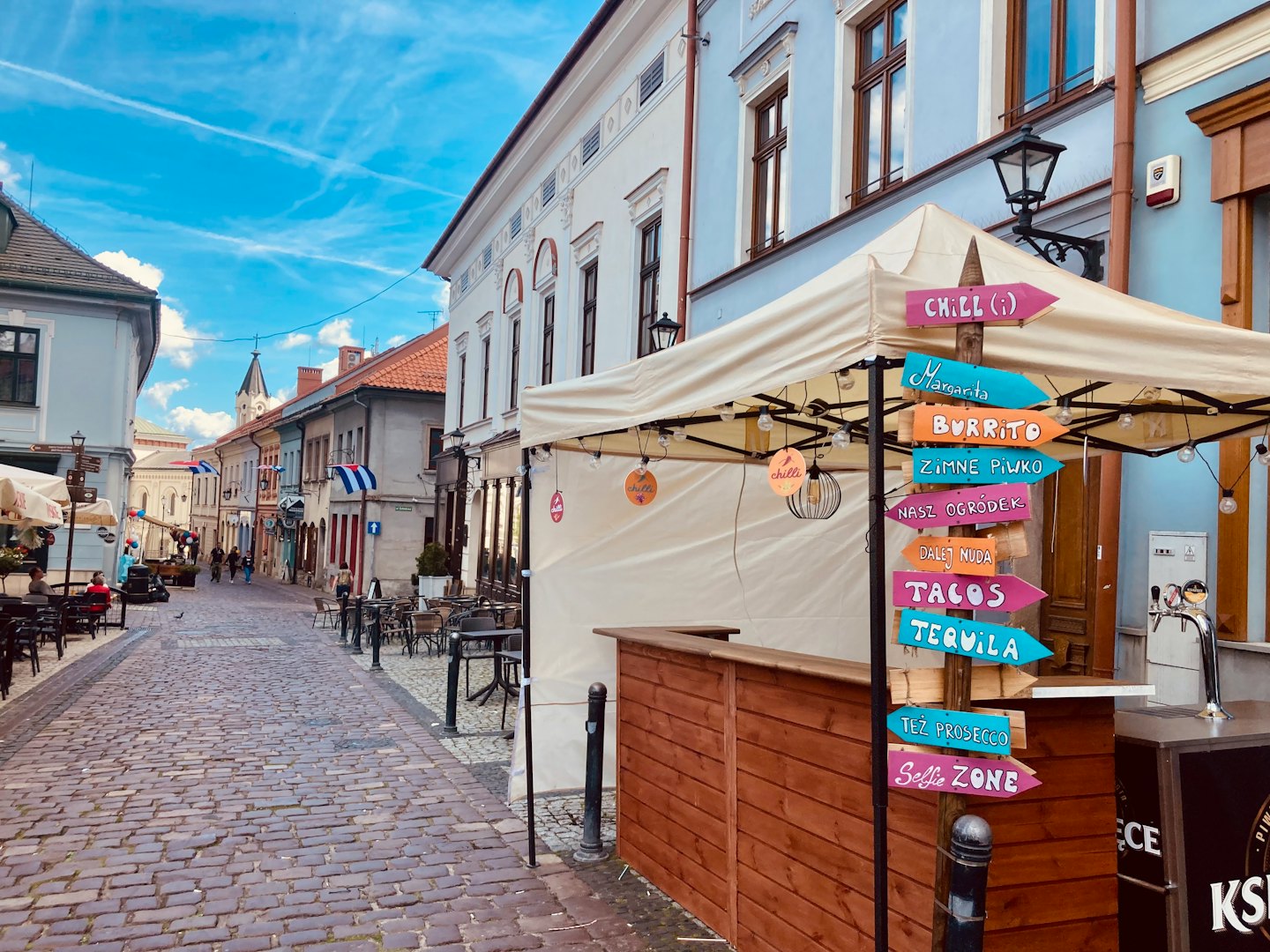 Colorful signpost stands outside a bustling European cafe.